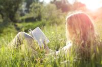 Vrouw leest boek in het gras