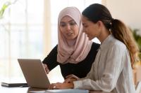 Twee vrouwen praten en wijzen naar pc