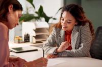 Twee vrouwen bekijken papieren en glimlachen
